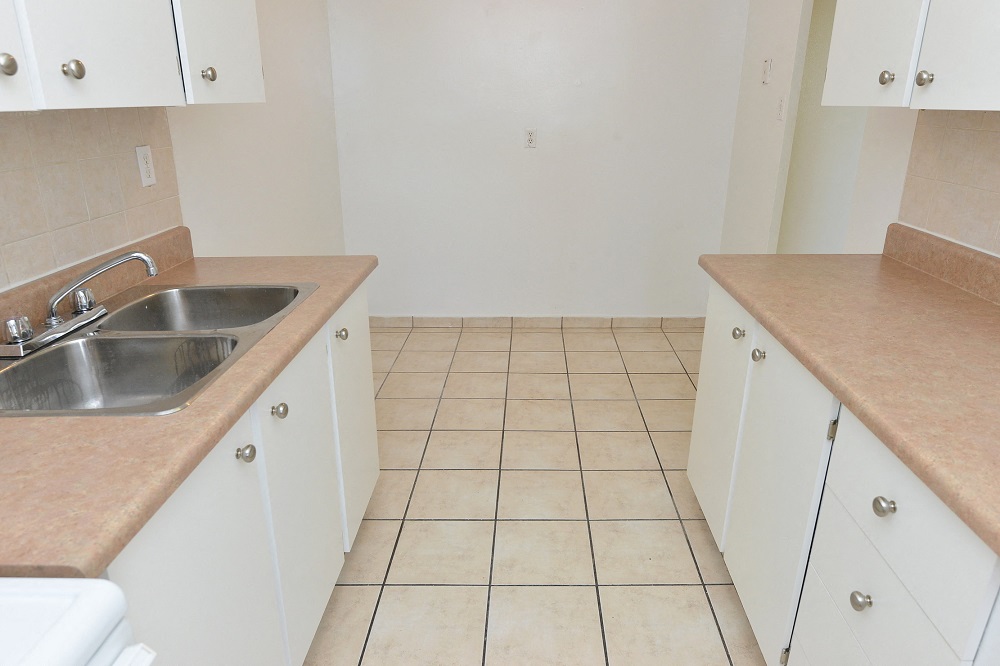 an empty kitchen with white cabinets and a sink